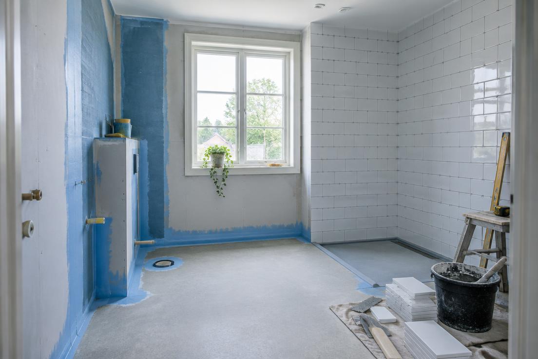 Ljust badrum under renovering med synligt underarbete och nytt kakel