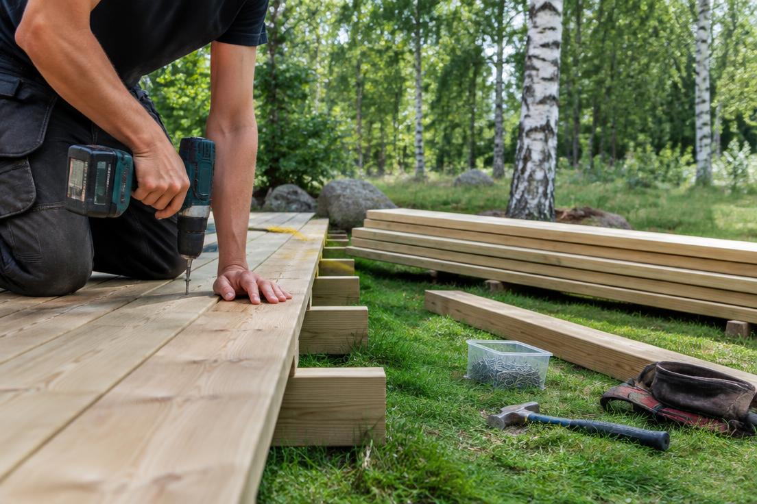 Bygge av träaltan i svensk trädgård med reglar, skruvverktyg och gräsmatta